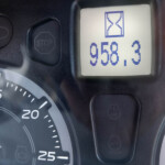 Close-up of a car instrument cluster showing the tachometer and a digital readout reading 950.3 with an hourglass icon above.