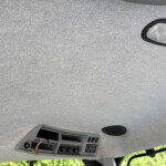 Overhead console of a vehicle ceiling with exposed wiring and empty slots from a removed panel