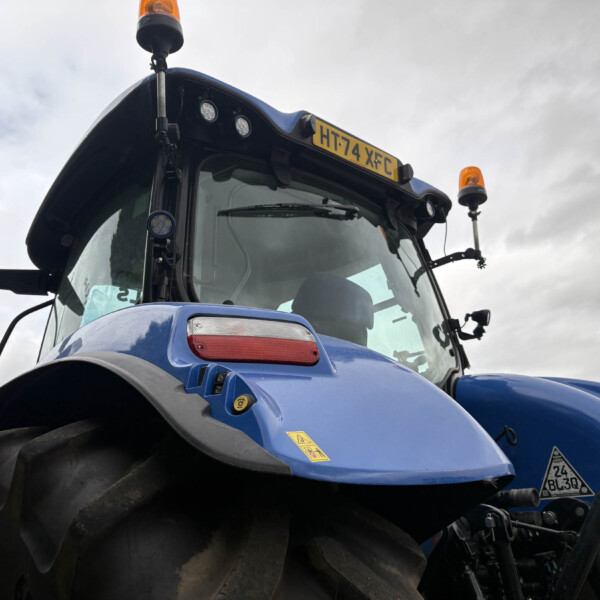 Front view of a blue tractor with large tires, two orange beacon lights, and a yellow license plate HT74 XFC on the cab roof Papc?