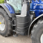 Front-left view of a blue New Holland T7.300 tractor, featuring a large front tire, stepping platform, and cabin window.