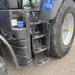 Close-up of a blue tractor unit showing steps, a blue cap, and a large rear tire with tread visible.