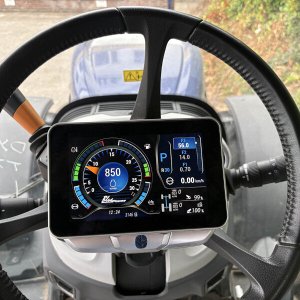 Steering wheel frames a digital instrument panel showing RPM around 850 and various vehicle readouts in the center.