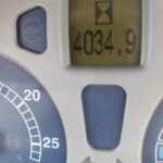 Close-up of a medical control panel: a blue STOP button on the left and a yellow display showing the value 403.9 with an hourglass icon above it. A partial blue dial with number marks is visible to the left.