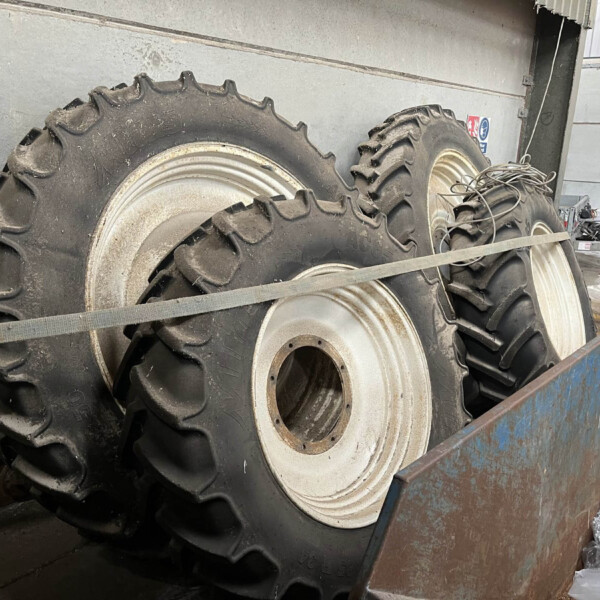 Large heavy tractor tires stacked in a truck bed inside an industrial space, dusty and rugged equipment visible in the background.