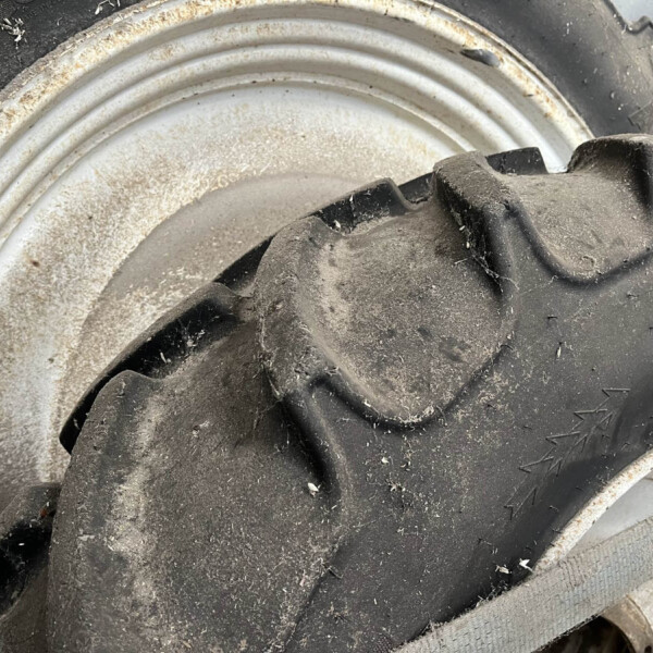 Close-up of a dirty tire mounted on a white rim, with mud and dust on the surface.