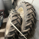 Large dusty tractor tire stack with tangled cables on top in a cluttered workshop.
