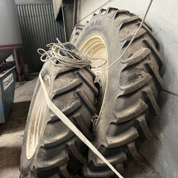 Large dusty tractor tire stack with tangled cables on top in a cluttered workshop.