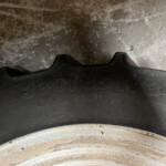 Close-up of a car tire showing worn tread and embossed sidewall markings (numbers and letters visible).