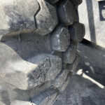 Close-up of thick, dirty tire treads on heavy equipment vehicle.