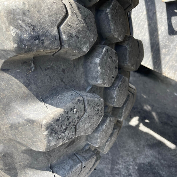 Close-up of thick, dirty tire treads on heavy equipment vehicle.