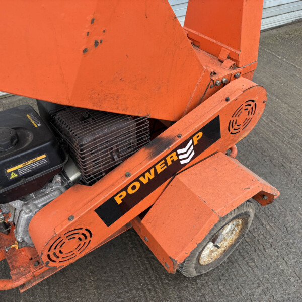 Orange construction lift with engine housing and warning labels visible on a concrete surface area.