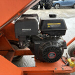 Close-up of an orange machine frame with a black 420cc gasoline engine and warning label.