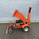 Orange construction lift with guard rails positioned in front of a gray corrugated metal wall/door.