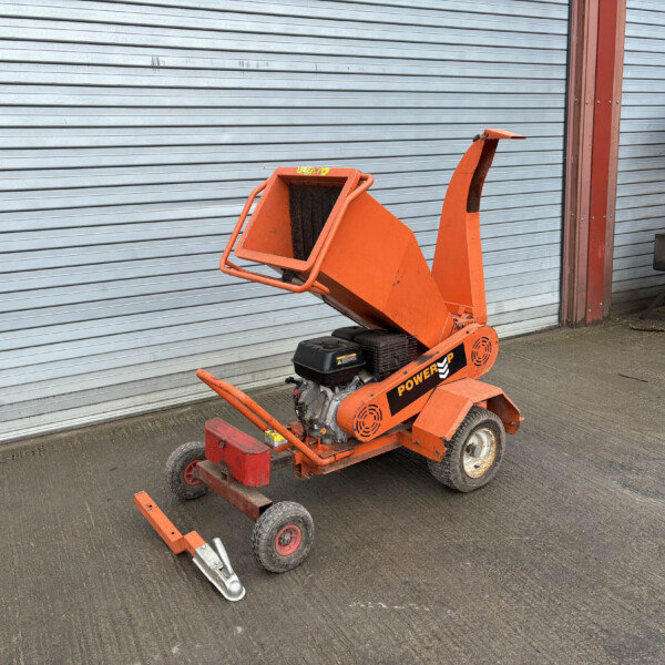 Orange industrial lift parked beside a grey corrugated metal shutter.