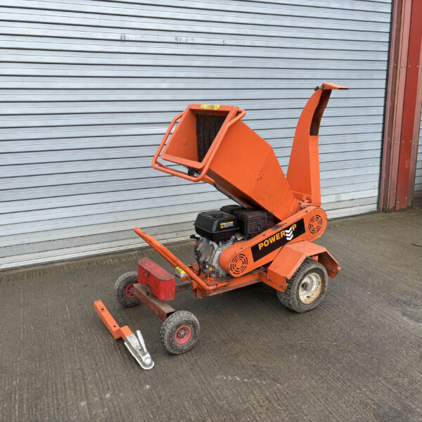 Orange mobile construction lift with an extended arm resting on the ground in front of a gray corrugated metal shutter.