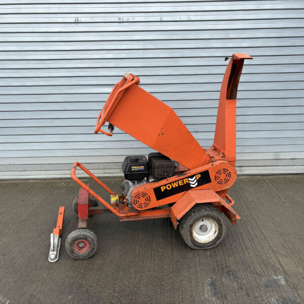 Orange construction lift with guard rails positioned in front of a gray corrugated metal wall/door.