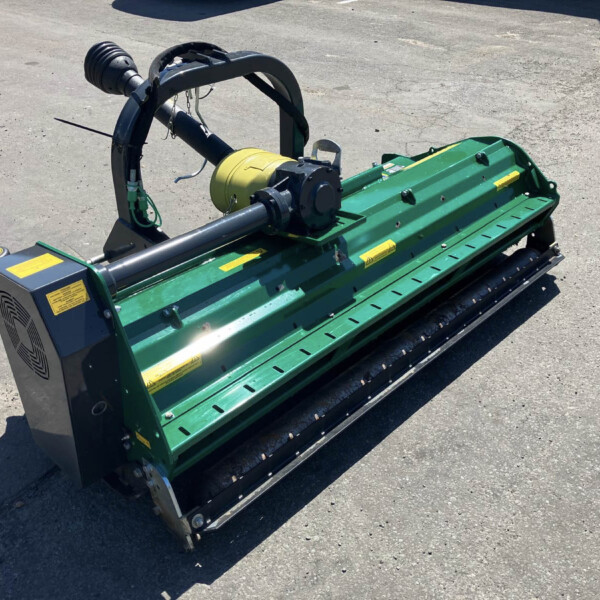 Green farm implement with a yellow hydraulic motor and black frame resting on a paved surface, likely a mower or shredder attachment.