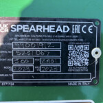 Close-up of a black metal identification plate on green equipment showing the SPEARHEAD branding, CE mark, a QR code, handwritten serial information, and 'MADE IN ITALY' at the bottom.