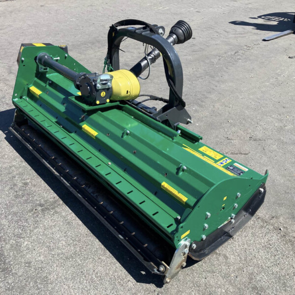 Green industrial attachment with a yellow motor sits on a metal frame on pavement, likely a hydraulic drive component of a larger machine.
