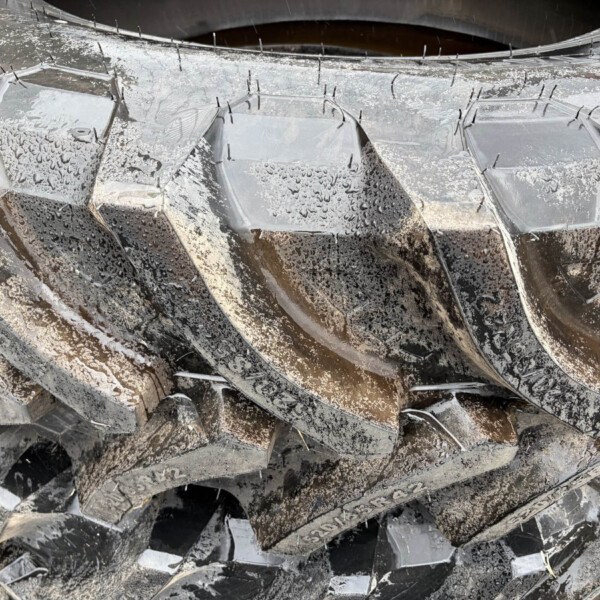 Pile of jagged broken glass shards scattered on muddy ground, with grime and dirt coating them
