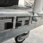 Close-up of a silver trailer frame with a data plate that reads 'FOR WILLIAMS TRAILERS LTD' and shows weight information on the badge.