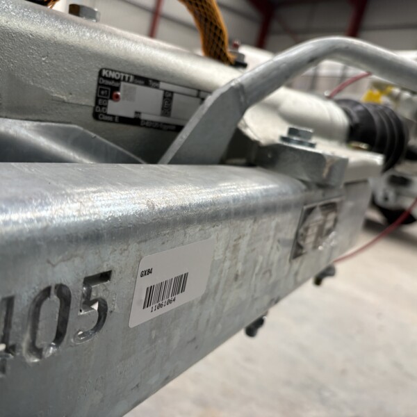 Close-up of a gray metal industrial machine with a barcode label and the model number GX84 visible on the side.