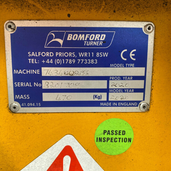 Close-up of a blue Bomford Turner machine nameplate on a yellow surface, showing model and serial information and a CE mark.