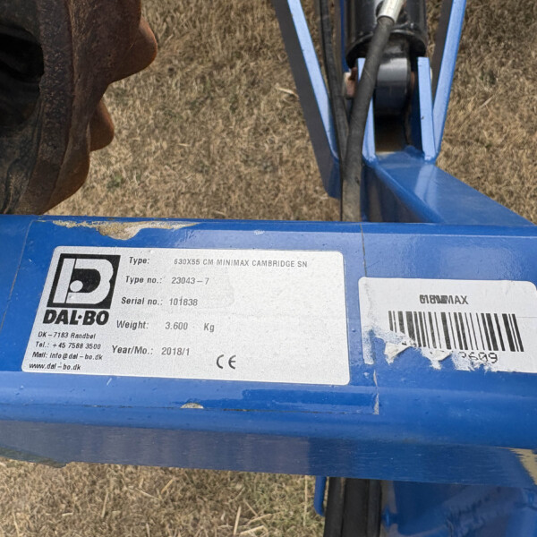 Blue industrial machine frame with a metal information label and barcode, showing model/serial details.