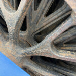 Close-up of rusted interlocking metal bars with hollow cutouts and rough, flaked coating. (Close macro view)