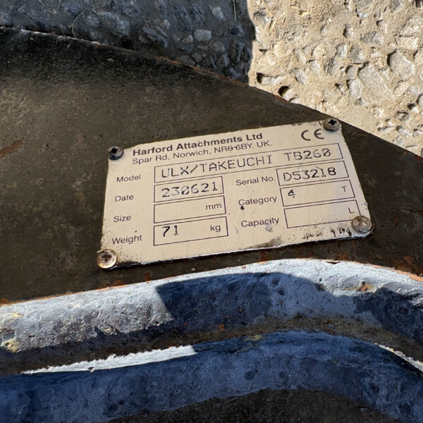 Close-up of a rusted metal plate with an informational label from Harford Attachments Ltd, showing model/serial fields.