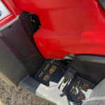 Close-up of a red vehicle body with a textured black step and a warning label on the left side.