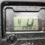 Close-up of a rugged digital display on a wet, dirty surface, with condensation obscuring the readout and a numeric value partly visible.