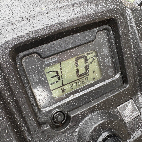 Close-up of a black rugged waterproof case covered in numerous water droplets on its surface.