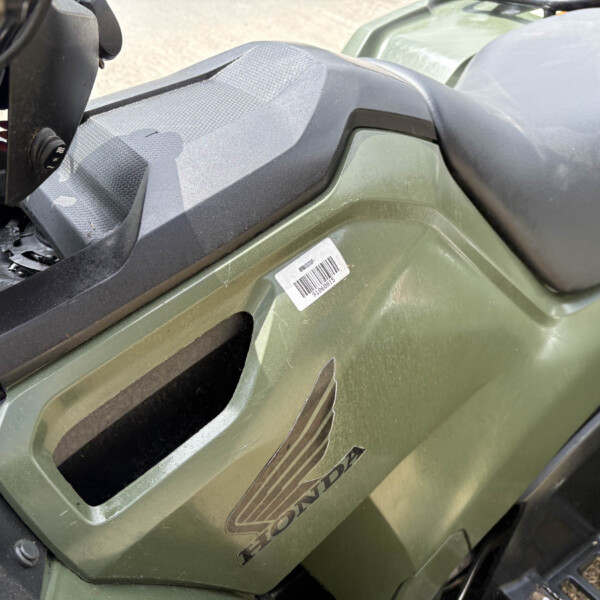 Close-up of a green Honda vehicle body panel with a textured black seat area and a barcode sticker visible on the side panel.
