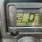 Close-up of a car gear indicator showing the number 0 with raindrops on the dashboard.
