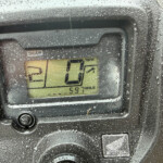 Close-up of a waterproof bike computer display showing gear indicator and speed on a wet surface.