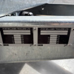 Close-up of a trailer's identification plates on a metal frame, showing 'IFOR WILLIAMS TRAILERS LTD' and weight specifications.