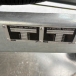 Close-up of two Ifor Williams Trailers Ltd identification plates mounted on a metallic trailer frame, showing weight specifications and serial details.