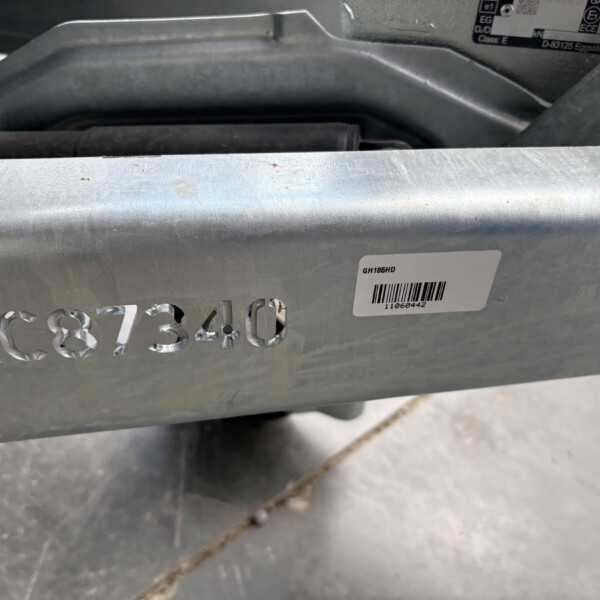Close-up of a gray metal surface with embossed digits and a white barcode label reading GH106HD on the edge of a frame.