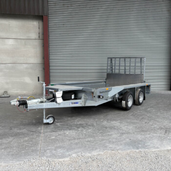 Industrial yard scene with a utility trailer in front of a large gray corrugated metal roller shutter; a yellow door is on the right.