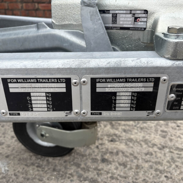 Close-up of a silver trailer body with plaques reading IFOR WILLIAMS TRAILERS LTD and weight specs, wheel visible beneath.