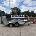 Trailer sits in an industrial yard beneath a Russell's sign, with additional equipment and blue sky above.