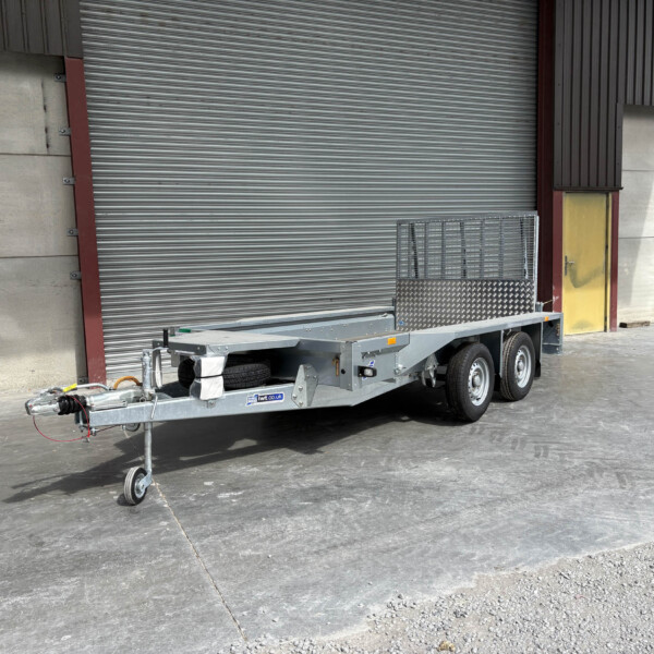 Industrial trailer parked near a warehouse with large corrugated metal roller door behind it at a loading area.