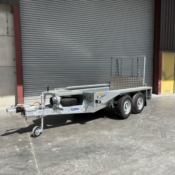 Industrial loading dock with a closed corrugated metal roll-up door, a yellow door to the right, and a utility trailer in the foreground.