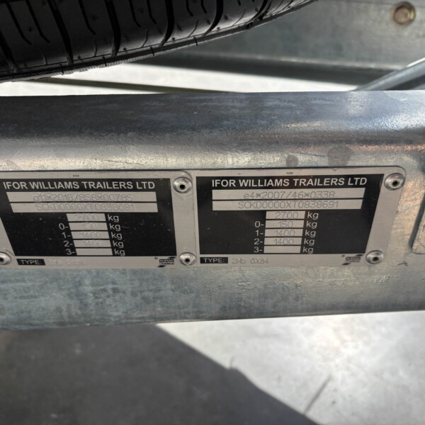 Close-up of two Ifor Williams Trailers identification plates on a metal chassis, with a tire visible above them.