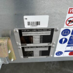 Close-up of a trailer rear with identification plate reading 'IFOR WILLIAMS TRAILERS LTD' and a barcode, plus safety labels nearby.