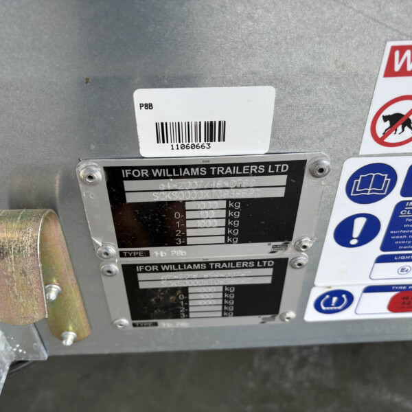 Close-up of a trailer rear with identification plate reading 'IFOR WILLIAMS TRAILERS LTD' and a barcode, plus safety labels nearby.