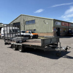 Industrial warehouse with metal siding, loading bays, and several company vans in a fenced yard.
