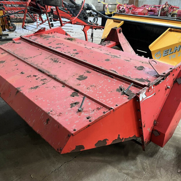 Red agricultural implement with a yellow ELHO TR 220 component, showing chipped paint and exposed metal in a workshop setting.