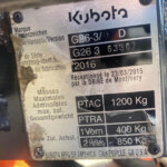 Close-up of a Kubota identification plate with model G26-3 and date 2016 on a metal surface in a dusty, taped area